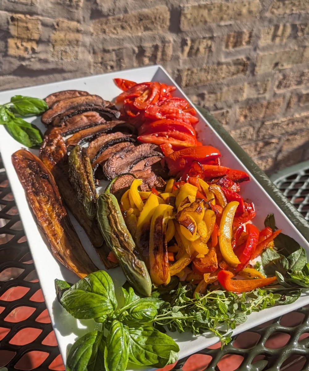 Platter of grilled peppers, eggplant and tomatoes with fresh basil